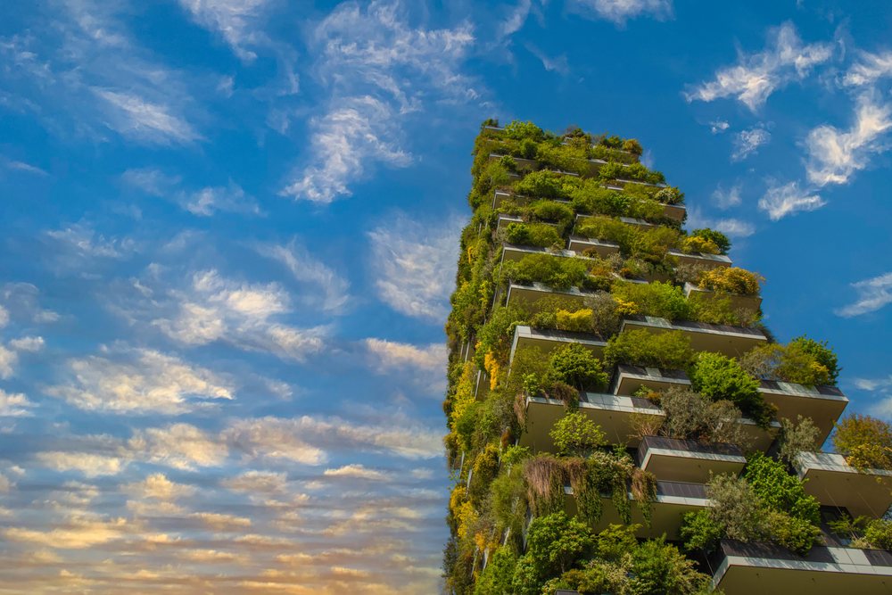 Der Bosco Verticale: zwei Wohntürme, deren Balkone über alle Stockwerke mit ausgewachsenen Bäumen bepflanzt sind, vor blauem Himmel.